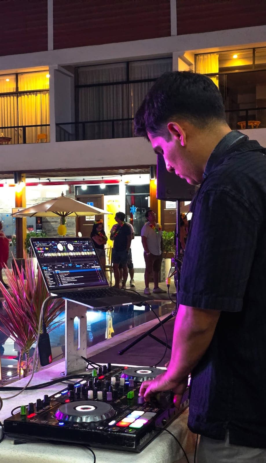 DJ joven mezclando música en una consola durante una fiesta nocturna al aire libre.
