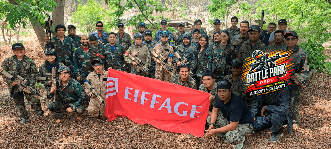 Grupo en camuflaje con réplicas de armas posando con una bandera roja de Eiffage.